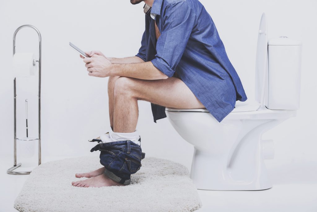 Young man using laptop on toilet